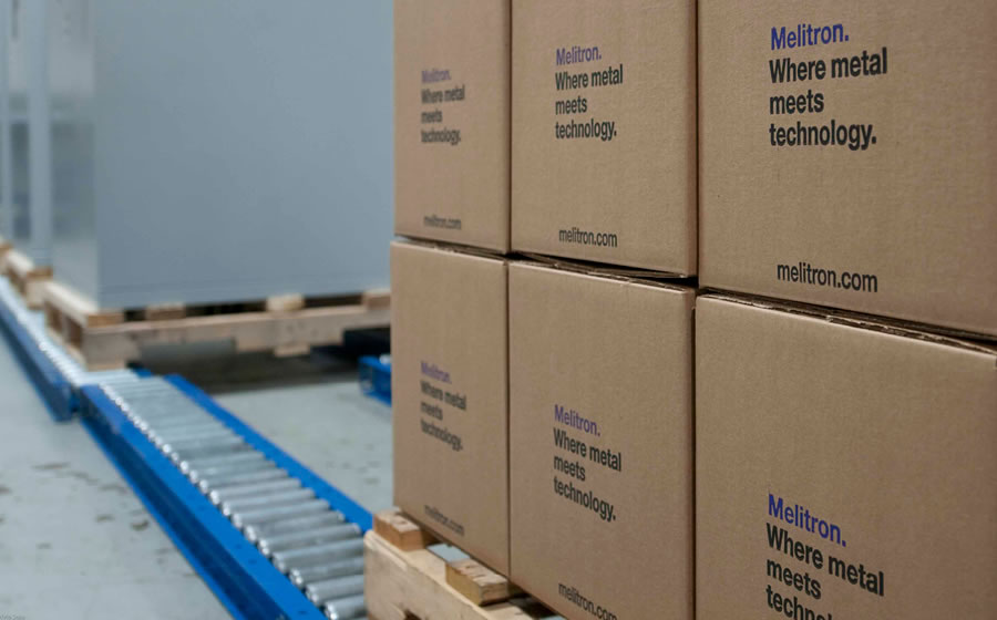 A stack of Melitron-branded cardboard boxes on a wooden pallet are ready to be shipped out of the factory.